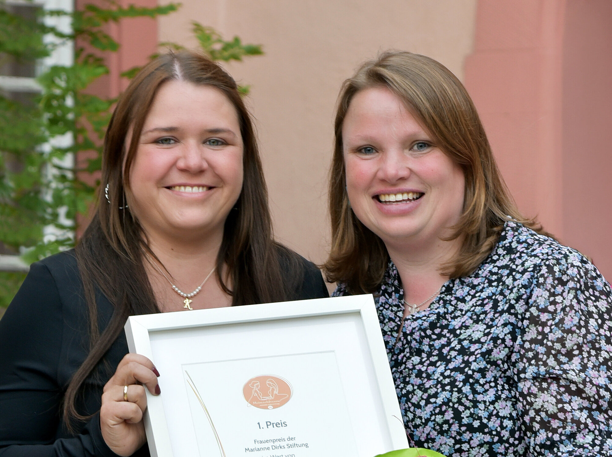 Zwei Frauen mit Urkunde und Blumenstrauß